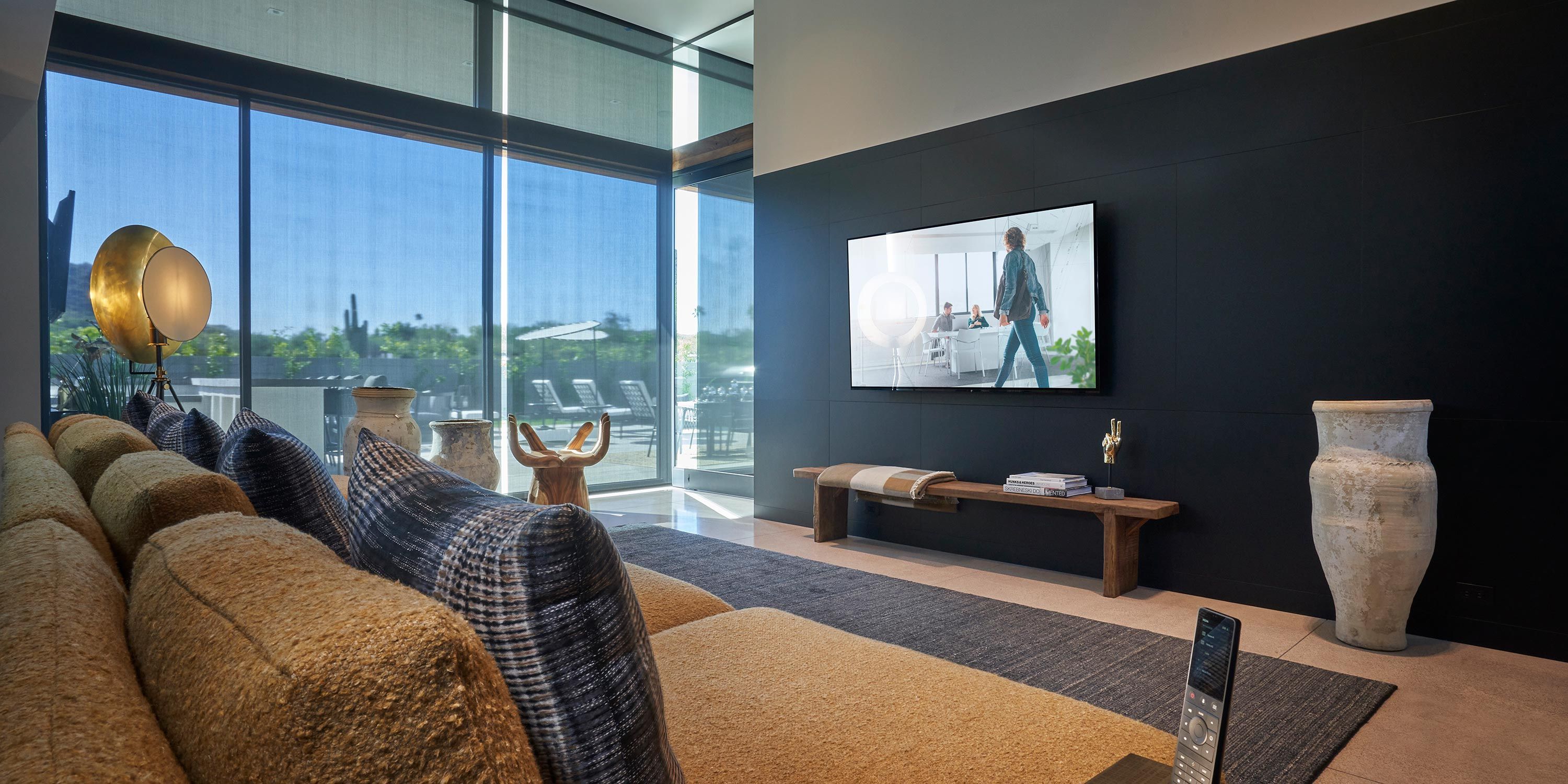 A sophisticated media room with a large screen, plush seating, and expansive windows allowing natural light, perfect for movie watching and relaxation.