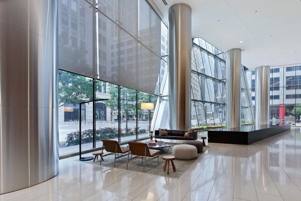 A sleek lobby with towering windows, minimalist decor, and polished stone flooring, creating a bright, welcoming atmosphere.