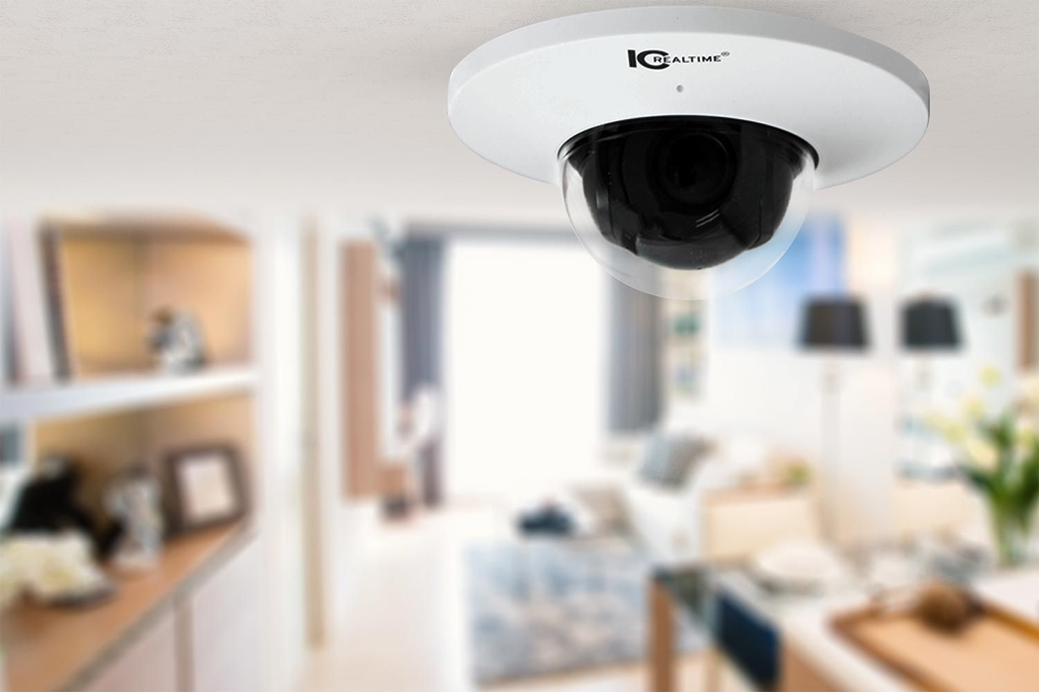 A ceiling-mounted dome surveillance camera with a blurred view of a modern living room in the background, highlighting smart home security. 