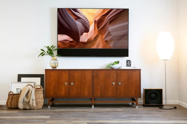 A stylish media room with a large TV mounted above a wooden console, decorated with plants and contemporary accents.